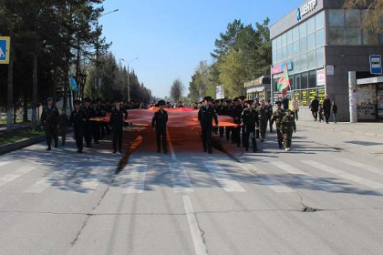 Самое большое в РФ Знамя Победы пронесли по улицам Искитима 